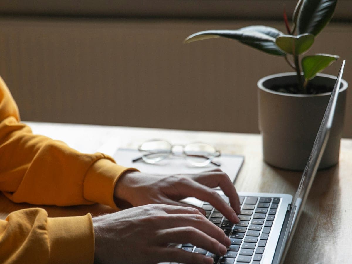 Hands typing on a laptop at a desk